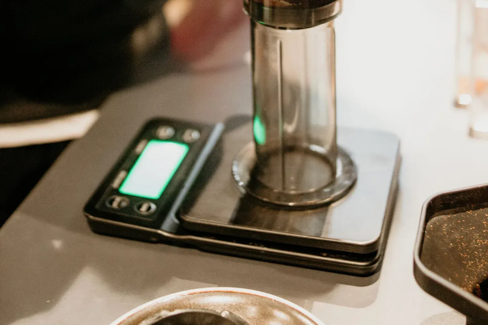 Un AeroPress posé sur une balance de préparation, le piston engagé dans la chambre