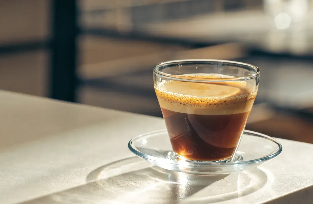 Un americano dans une tasse blanche, avec un anneau fin de crema encore posé sur la surface