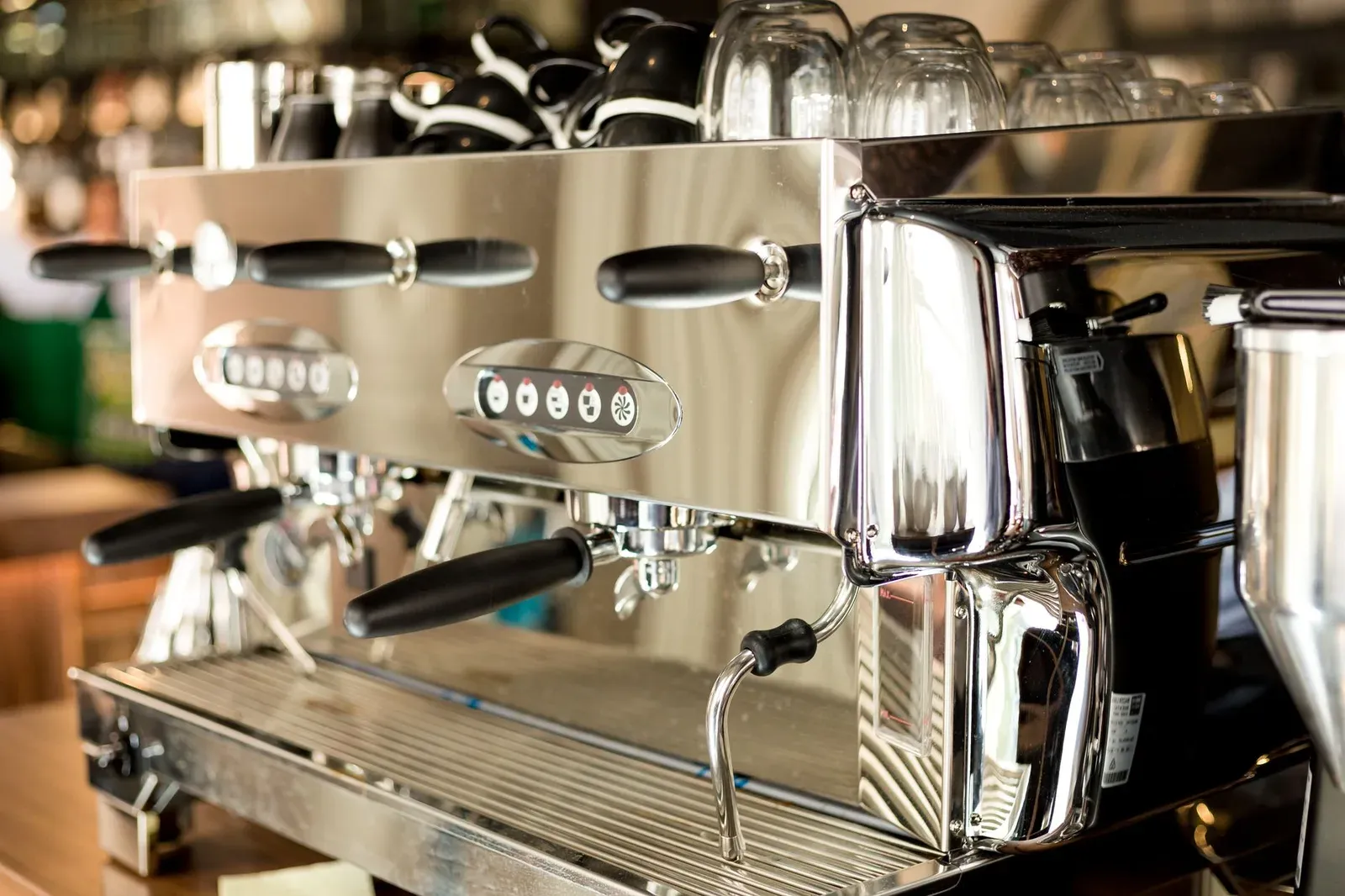 Une machine espresso deux groupes en inox, des tasses en chauffe sur le dessus