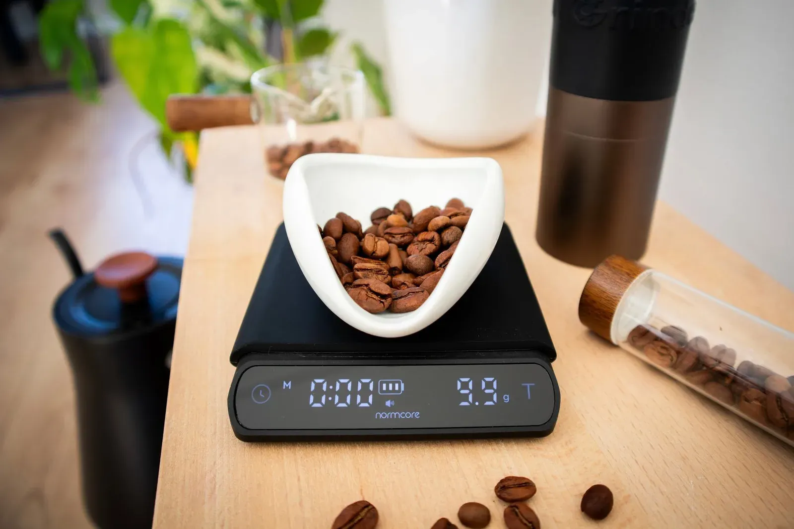 Des grains de café sur une balance numérique, près du matériel