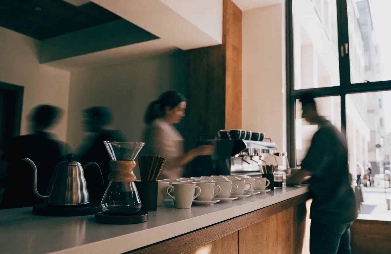 Un comptoir de café vu côté client, avec un paquet de grains pure origine, une balance et une machine espresso chromée
