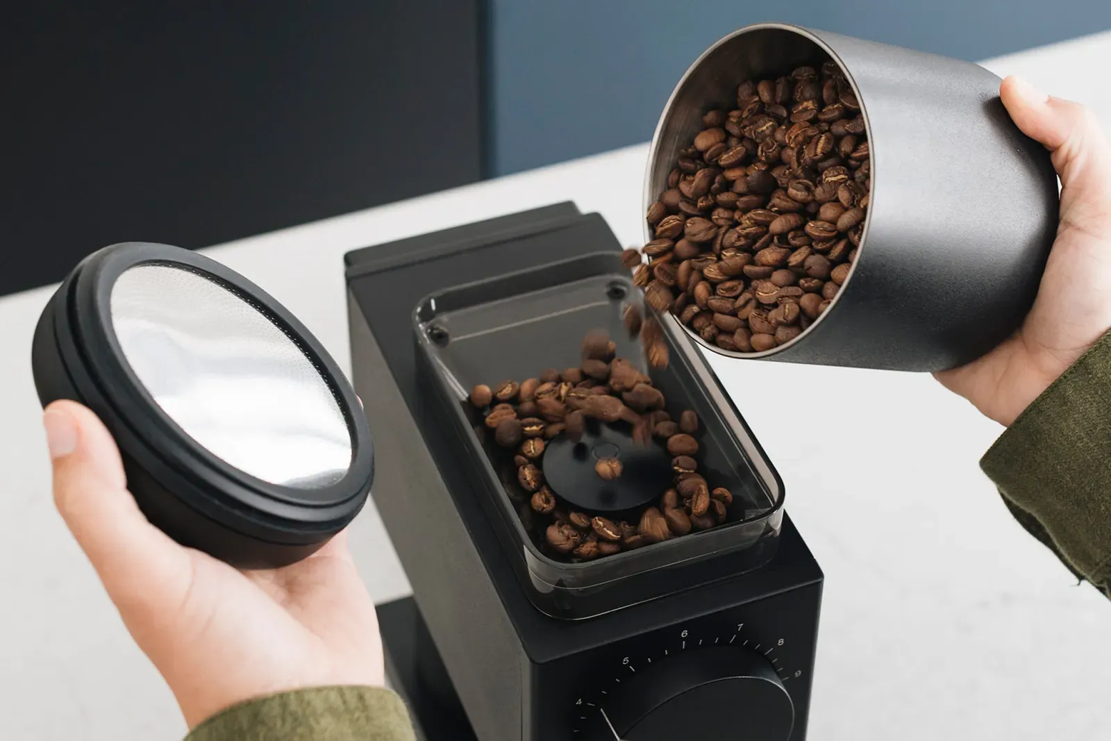 Des grains de café versés d'une boîte dans la trémie d'un moulin Fellow Ode Gen 2