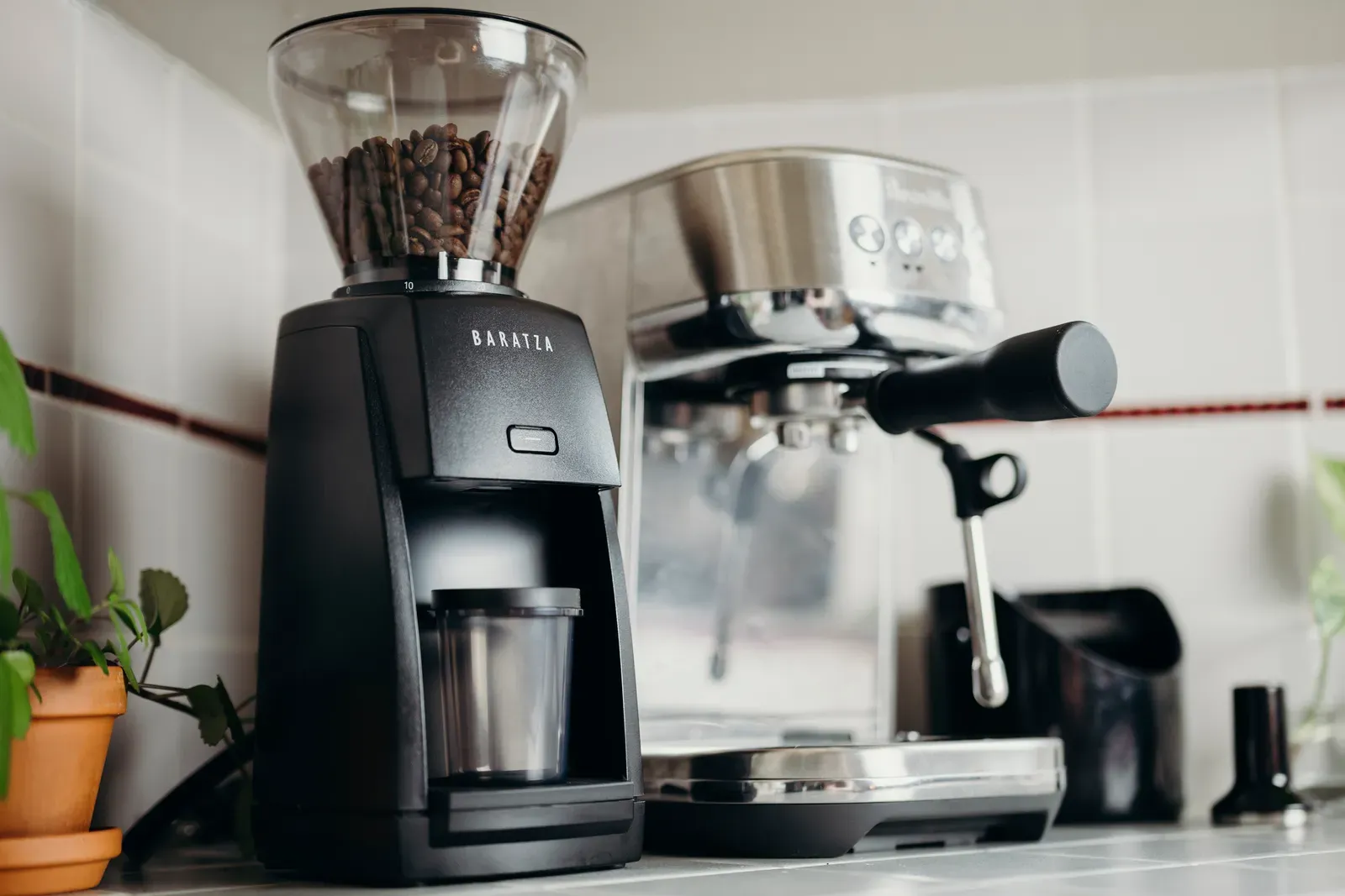 Un moulin Baratza Encore ESP à côté d'une machine espresso Breville, sur un plan de travail carrelé