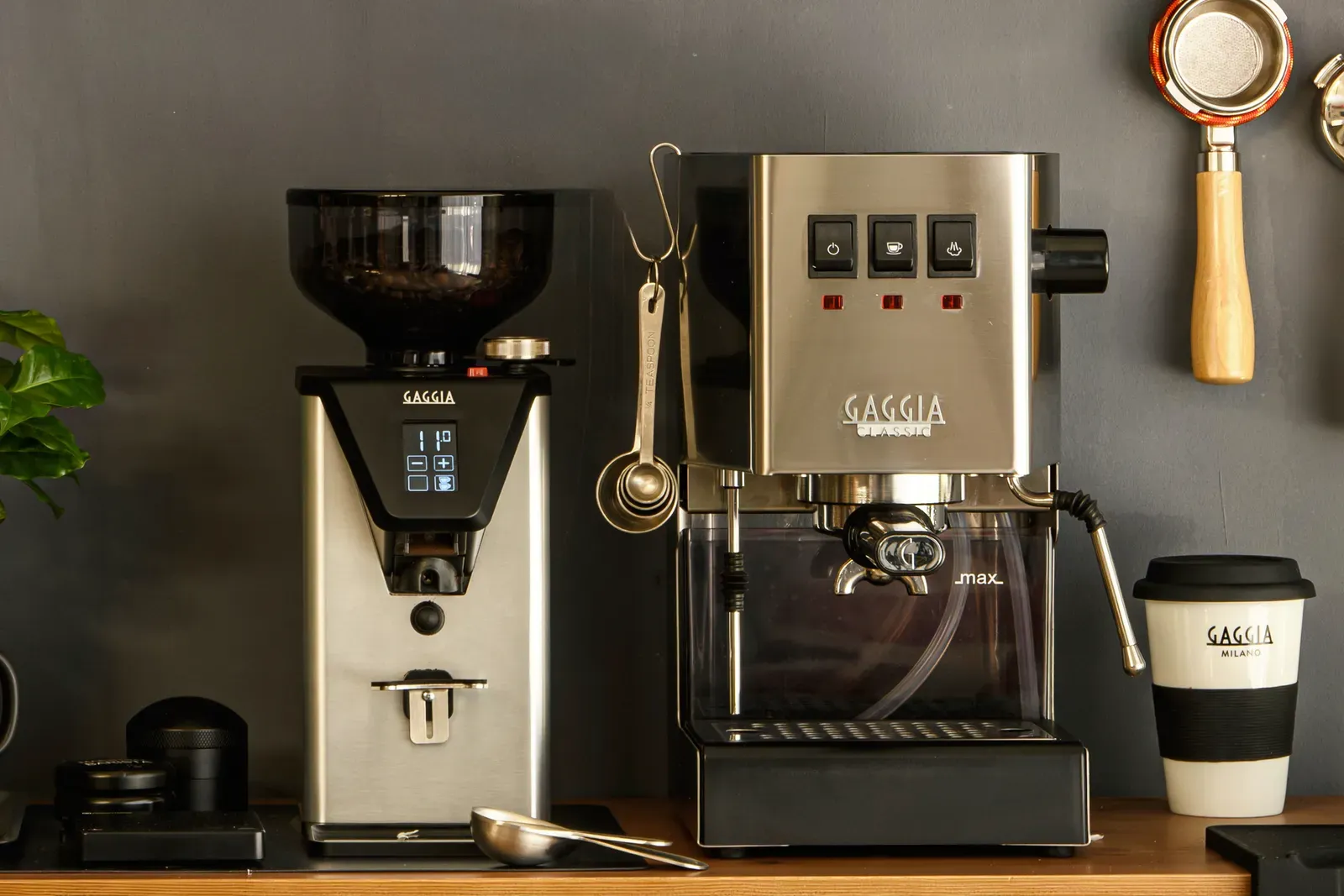 Une machine espresso Gaggia Classic et un moulin Gaggia côte à côte sur un plan de travail en bois, devant un mur sombre