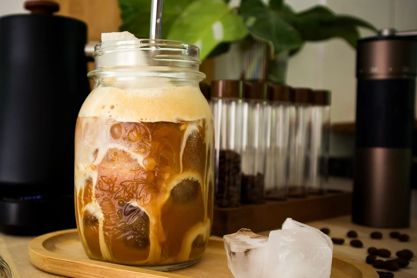 Un café glacé dans un bocal en verre, un moulin à main et une bouilloire derrière