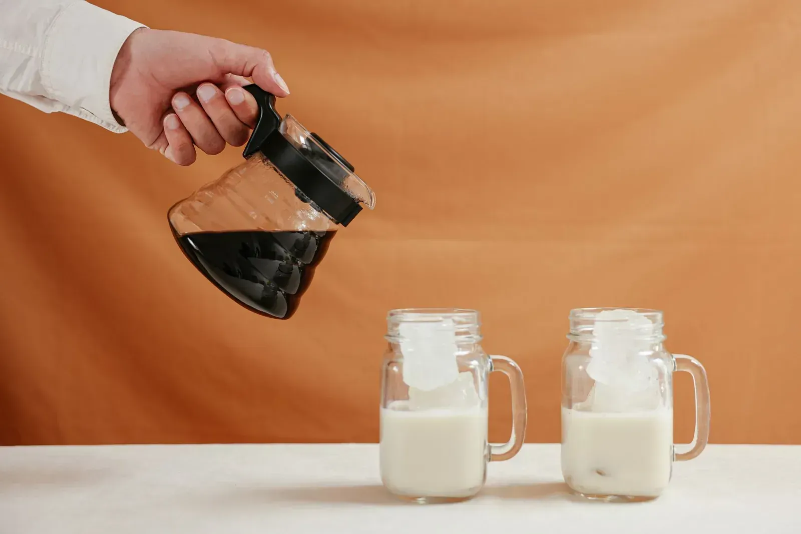 Du cold brew versé d'une carafe en verre dans des verres glacés