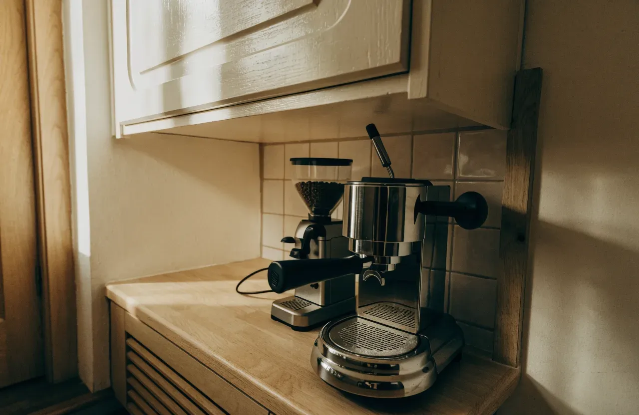 Une machine espresso étroite en inox sur un court pan de plan de travail, porte-filtre verrouillé, avec un meuble haut juste au-dessus