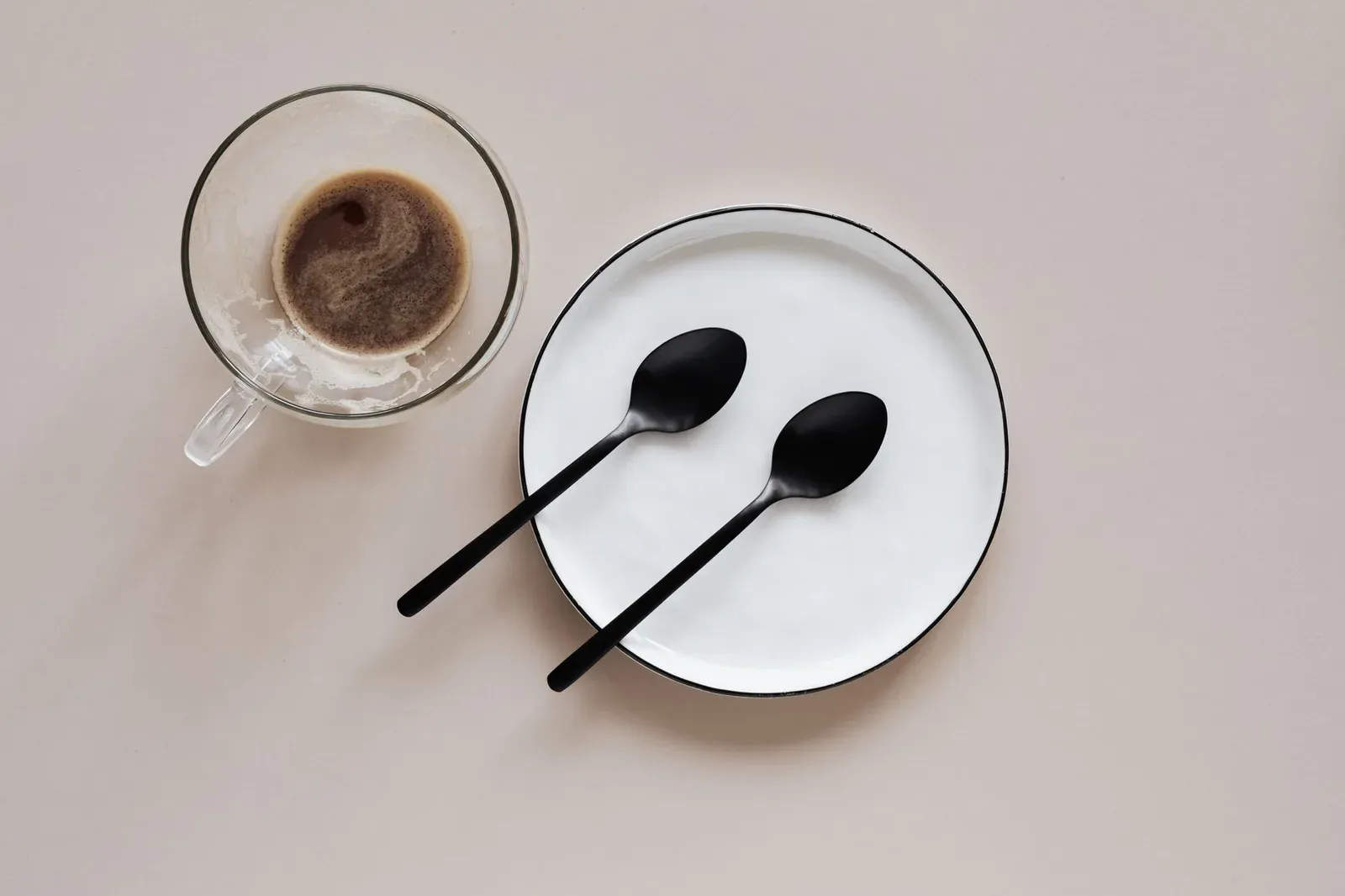 Une tasse de café vue de dessus, à côté de deux cuillères posées sur une assiette