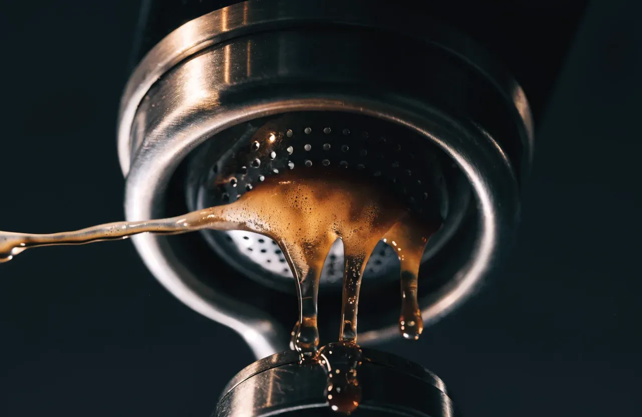 Un espresso coulant de façon irrégulière d'un porte-filtre sans fond sur fond sombre