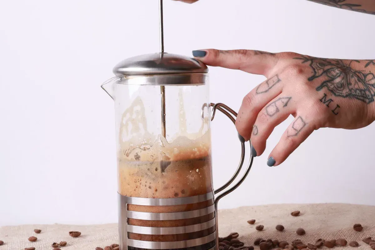 Deux mains poussent le piston d'une cafetière à piston
