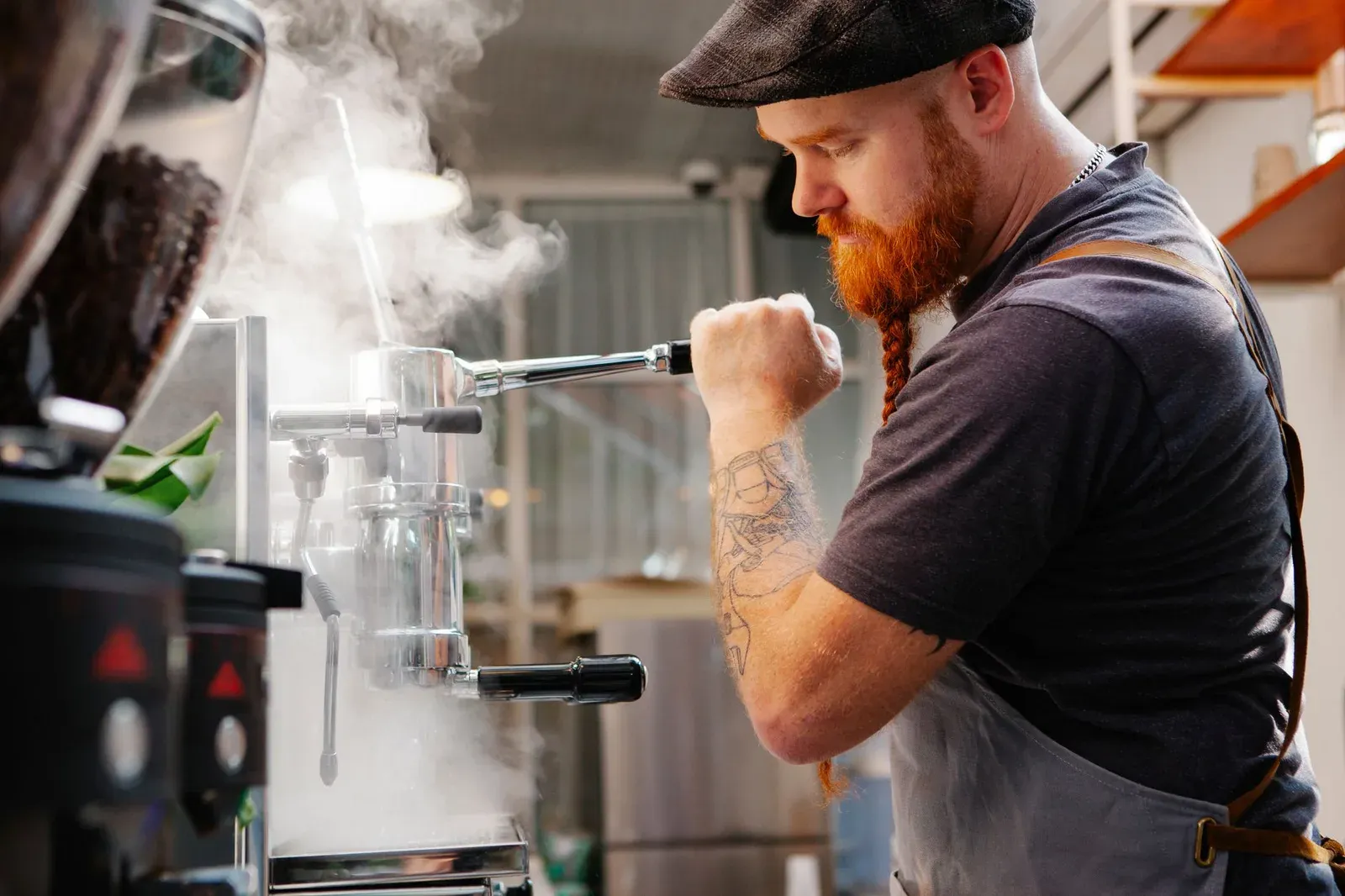Un barista abaisse le levier d'un groupe, la vapeur monte