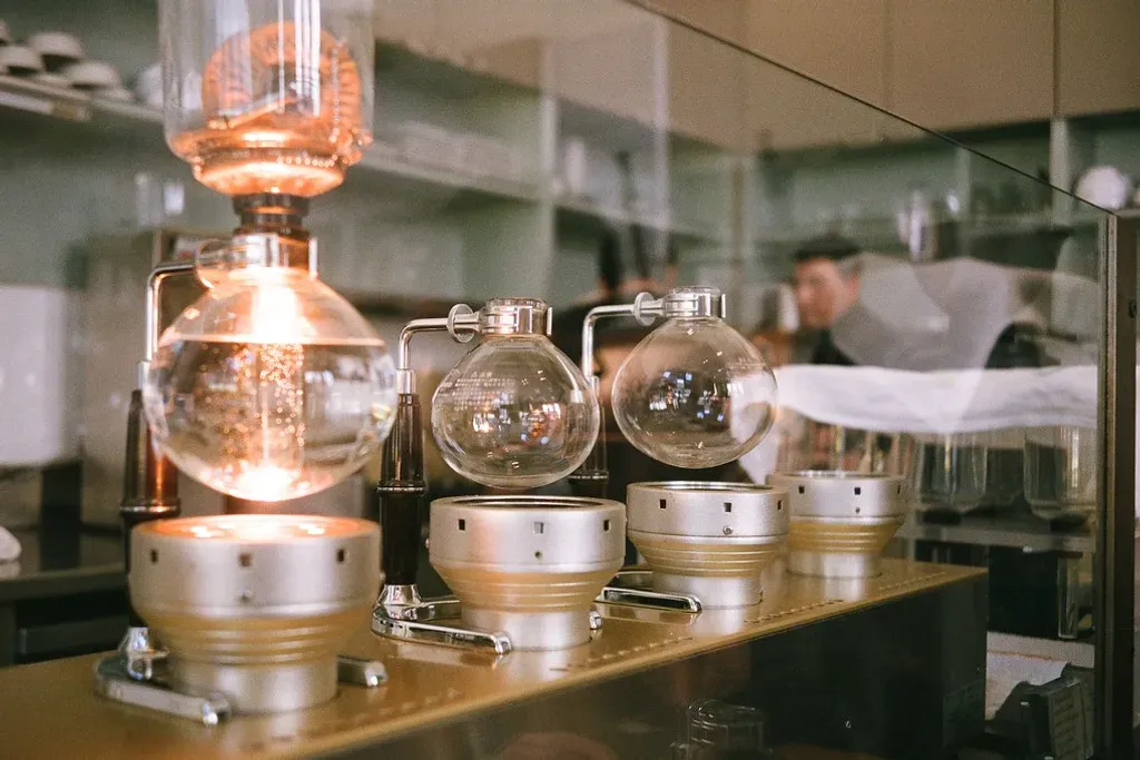 Une rangée de siphons en verre au-dessus de chauffages halogènes allumés, sur le comptoir d'un café