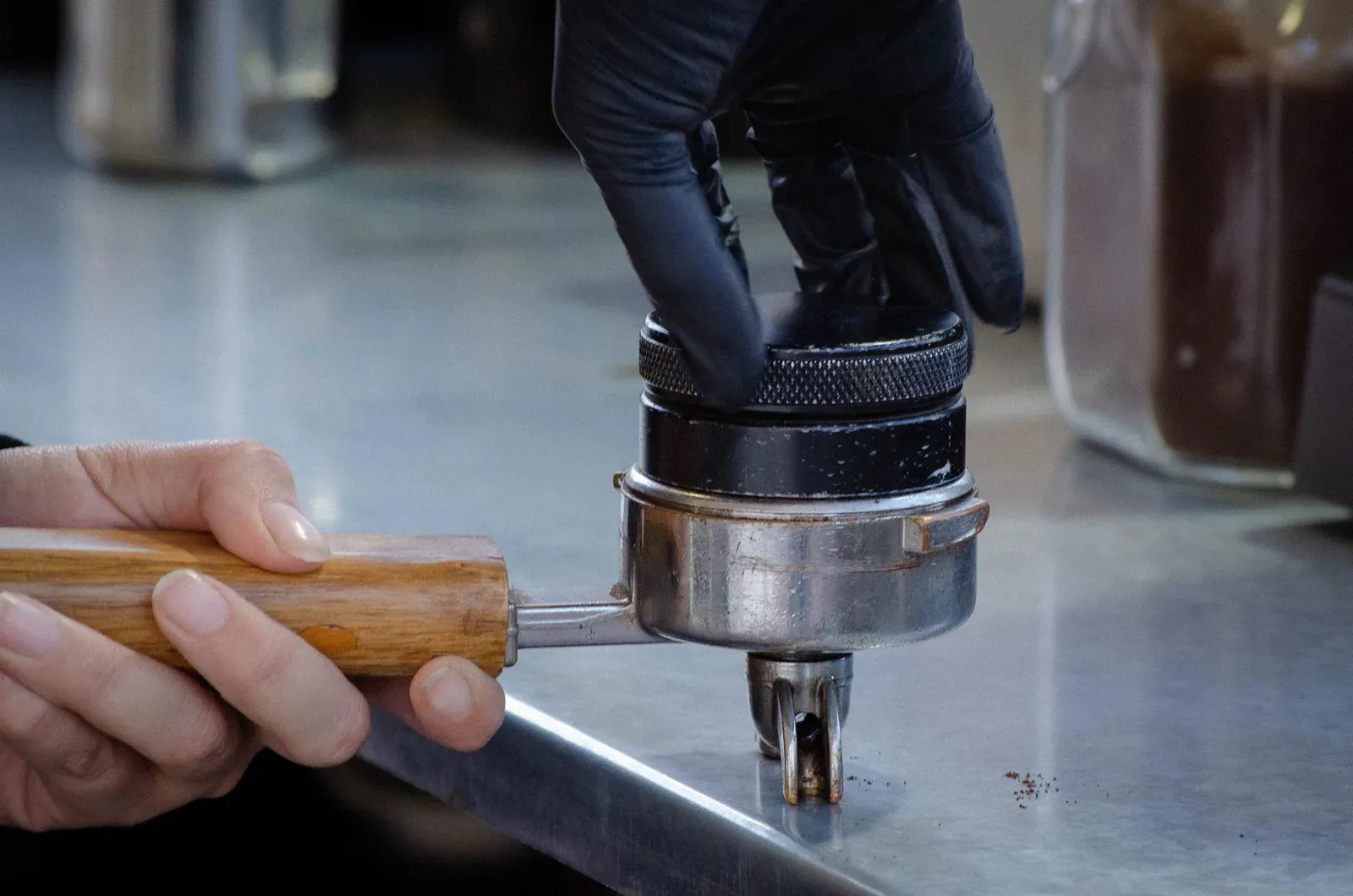 Les mains d'un barista pressant un tamper dans un porte-filtre