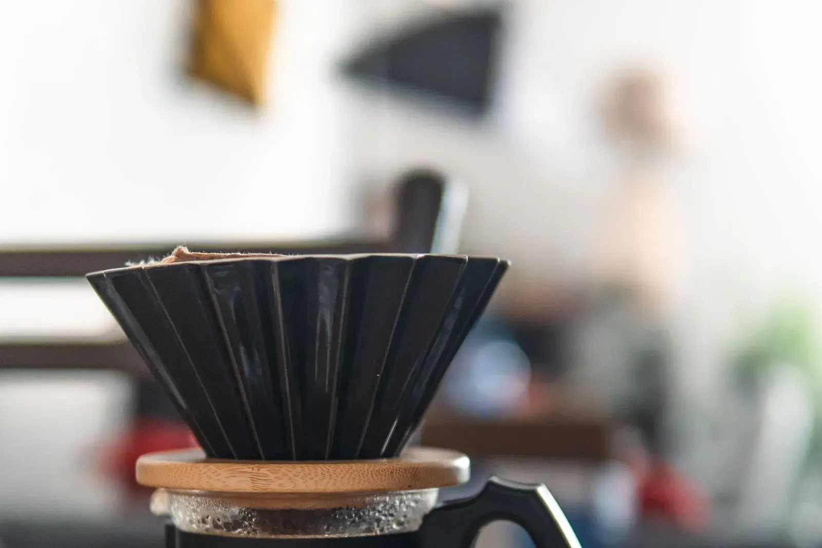 Un dripper V60 en céramique et une tasse posés sur une table en bois