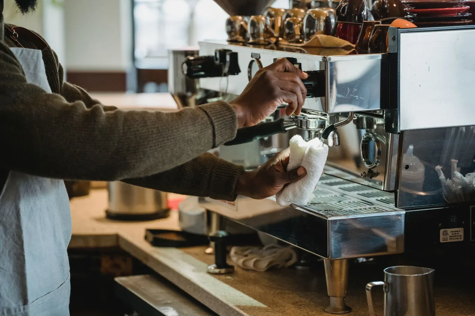 A barista wiping down an espresso machine at a café