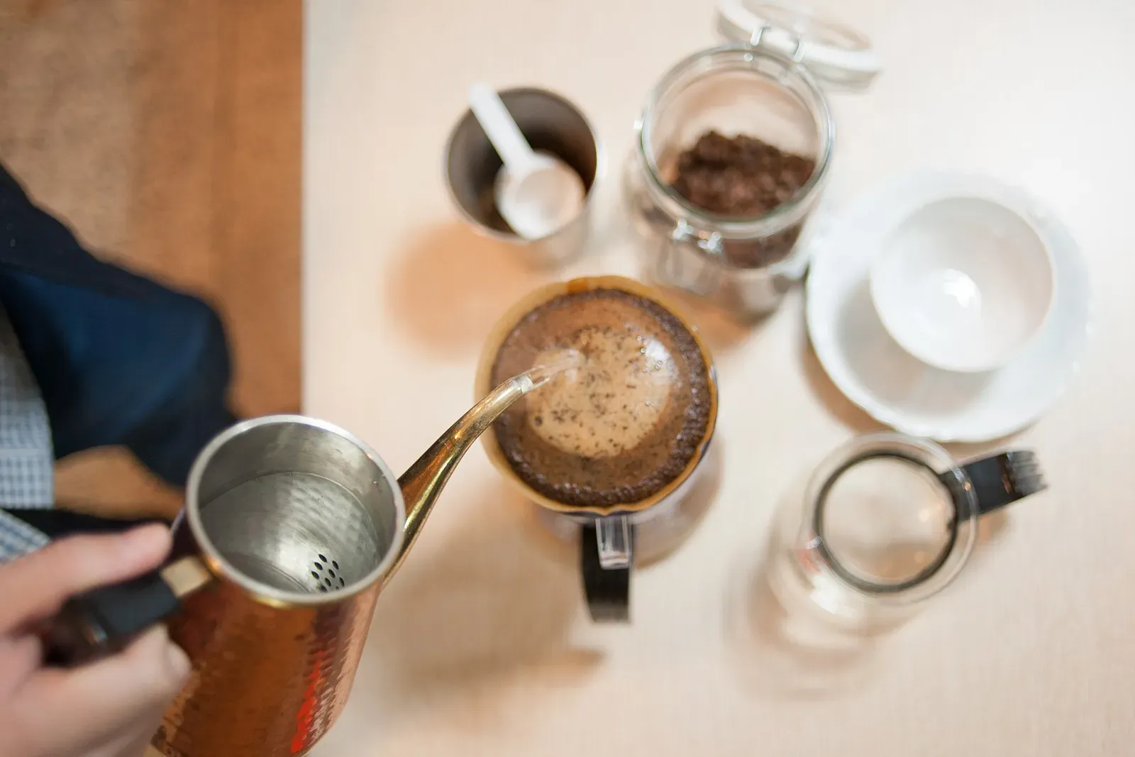 De l'eau versée d'une bouilloire col de cygne en cuivre sur un lit de café, vue de dessus